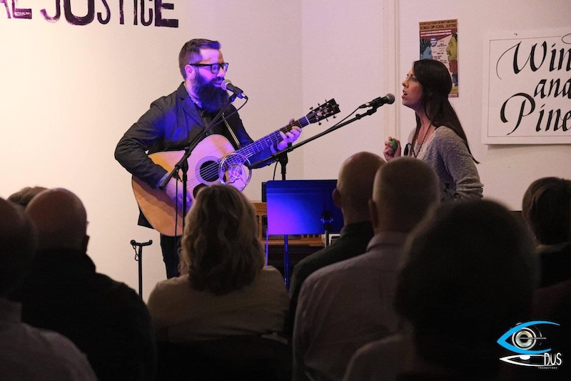 Barry playing guitar with Emily Smith as both sing in the act Wind & Pine.